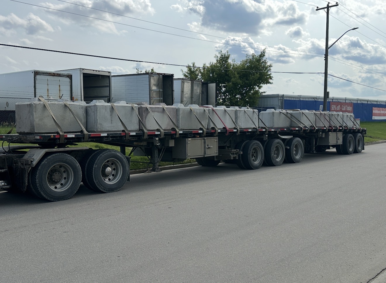Super B-train flat-deck fully loaded with concrete barrier blocks