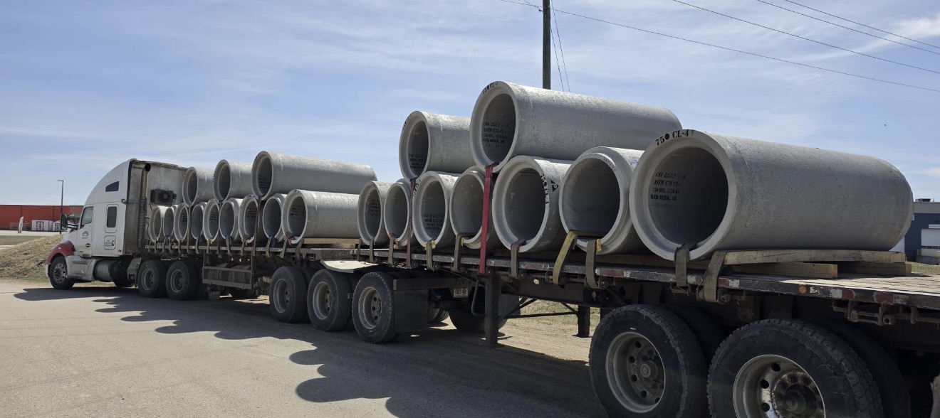Super B-train flat-deck loaded with large-diameter concrete cylinder sections