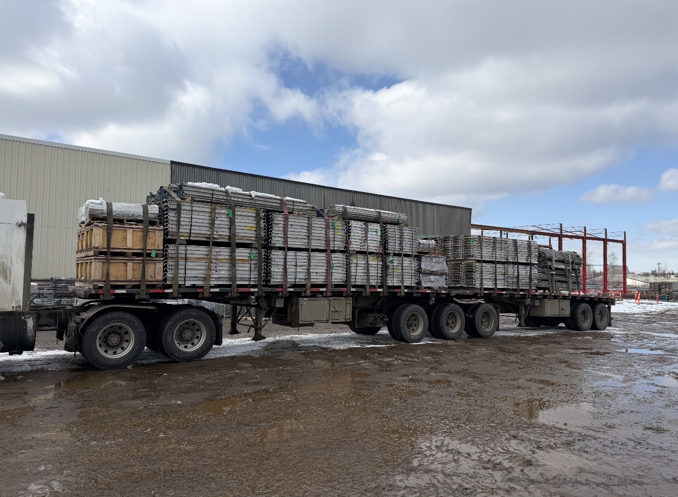 Super B-train flat-deck staged with scaffolding components ready to depart