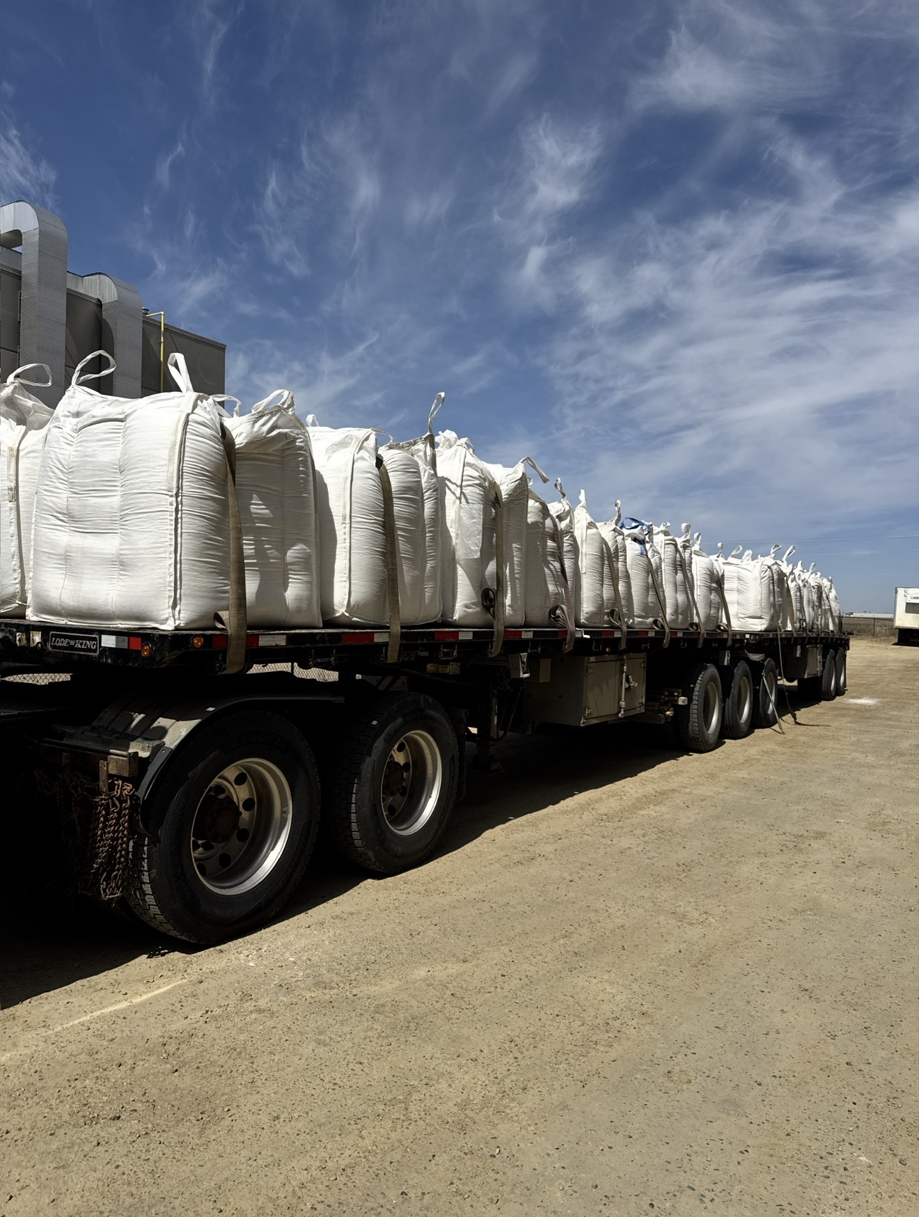 Flatbed trailer stacked with white bulk supersacks