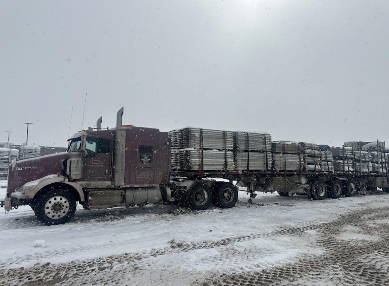Kenworth flatbed with scaffolding load in snowy Alberta yard
